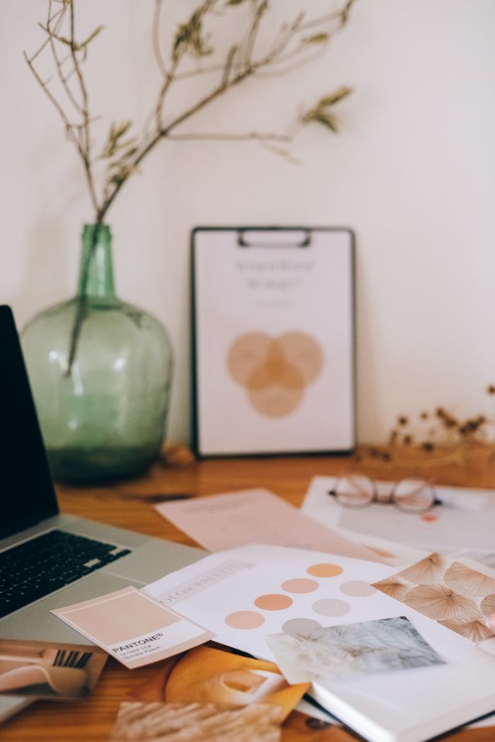 Artistic desk setup with documents and plant vase, inspiring creativity and organization.